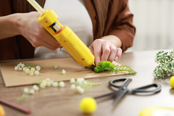 Wall Mural - Woman with hot glue gun making craft at table indoors, closeup