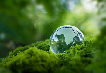 environmental concept - crystal globe on green moss in forest to protect nature. eco-friendly esg co