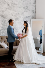 Wall Mural - groom in a blue suit tie and the bride in a bright studio