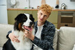 © LIGHTFIELD STUDIOS - In a modern apartment, a young man with red hair plays with his cheerful Australian Shepherd.