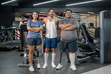 happy persons with prosthetic leg,athletic couple standing with trainer in indoors gym,looking at ca