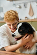 © LIGHTFIELD STUDIOS - A cheerful man with red hair enjoys heartwarming moments with his Australian Shepherd at home.