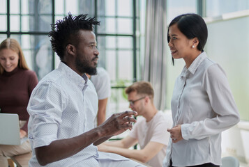 two businessmen talking against the background of their colleagues in the office