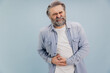 © anatoliycherkas - Senior man suffering from severe abdominal pain on blue background