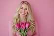 © Khawla - Portrait of cheerful young lady with romantic spring bouquet of tulips over pink studio background. Gorgeous blonde enjoying Woman's Day celebration, receiving flowers as special gift