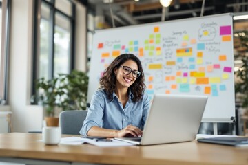 Wall Mural - Smiling woman working on laptop in modern office, colorful sticky notes in background.