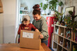 © Davor - Mother and son opening cardboard box package at home