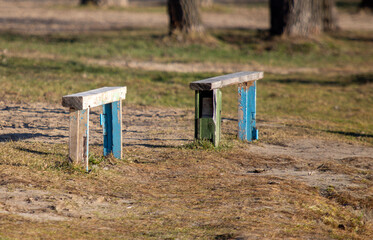 Two wooden benches are sitting in a grassy field