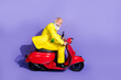 © deagreez - Profile photo of optimistic funny senior man boyfriend in yellow trendy costume riding motorcycle isolated on purple color background