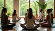 © Viktor - Group of people sit in lotus posture on mats during wellness retreat workshop. Individuals practice mindfulness meditation in light filled room. Nature view outside visible through large windows.