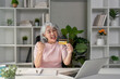 © Natee Meepian - Thrilled senior woman celebrating an online shopping win, holding her credit card in her home office