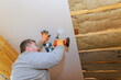 © ungvar - Construction worker uses power drill to secure drywall panels on ceiling during home renovation