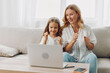 © SHOTPRIME STUDIO - Mother and daughter bonding on the couch while exploring an educational program on the laptop together