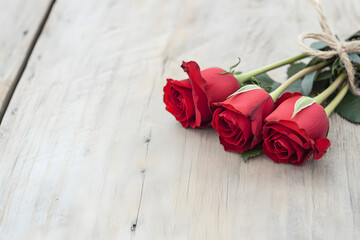 Wall Mural - Fresh red roses tied with twine on rustic wooden surface evoke romance and beauty