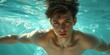 © CZALBERTO - Young man swimming submerged in a pool. Generative AI