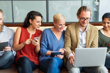 Wall Mural - group of diverse business people sitting together, using devices. smiling and engaged. business men 