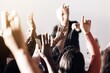 © Rawpixel.com - A diverse group of people raising hands in a classroom or seminar setting, with a focus on participation and engagement. Hands raised, diverse group, active learning.
