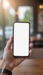 © Worldwide - Hand Holding Smartphone in Bright Café with Empty Screen Space