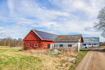 Canvas Print - Red barn with solar panels on the roof in the countryside