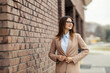© Dusan Petkovic - Portrait of smiling elegant businesswoman in suit adjusting blazer on city street downtown.