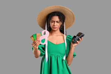 Wall Mural - Annoyed African-American woman with figure 8, credit cards and payment terminal on grey background. International Women's Day celebration