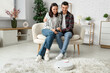© Pixel-Shot - Young couple using mobile phone for remote control of modern robot vacuum cleaner in living room
