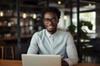 © nsit0108 - Portrait of a smiling young african american freelancer working on a laptop in a modern cafe