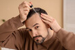 © Pixel-Shot - Handsome man applying serum for hair growth in bathroom, closeup