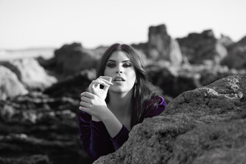 Wall Mural - beautiful young woman dancing flamenco among the rocks by the seashore, wearing a purple velvet dress with ruffles. The gypsy woman makes different expressions with her face and hands.