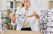 © Studio Romantic - Cropped shot of smiling optician giving you new glasses to improve vision. Positive ophthalmologist showing eyeglasses in optical store, ready to help patient in selecting eyewear. Eye health concept.