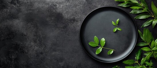 Leinwandbilder - Minimalist Flat Lay Image of a Black Plate with Green Leaves on Dark Textured Tabletop Creating an Elegant Empty Space for Text Addition