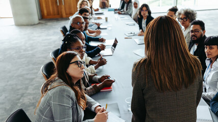 Wall Mural - manager leading business meeting with diverse team at large conference table