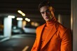 © Fotograf - A man wearing an orange jumpsuit leans against a wall, potentially as part of a uniform or costume