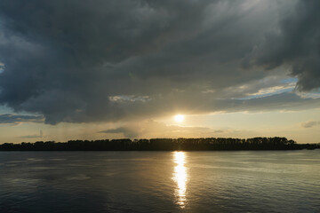 Wall Mural - A breathtaking sunset over the calm waters of the Volga River. The sky is painted in shades of orange, beautifully reflected on the surface of the river. Dark rain clouds. High quality photo