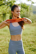 © SHOTPRIME STUDIO - Fit young woman exercising outdoors with resistance band, wearing a blue sports outfit, enjoying a sunny day in a green park setting