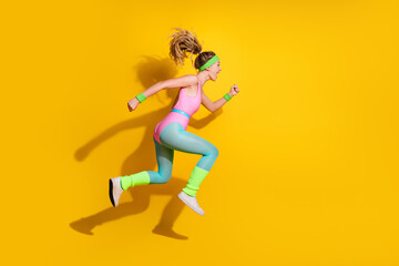 Wall Mural - Energetic young woman in retro fitness attire jumping against vibrant yellow background, embodying active lifestyle