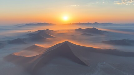 Wall Mural - Desert dunes at sunrise, aerial view of misty mountains.