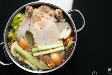 Wall Mural - Whole fresh turkey, cut onion, celery and spices in pot on stove, top view