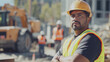 © Dirk - Hispanic construction worker with safety vest and hardhat on a construction site, face visible, other workers in background, heavy equipment in background. Safety at work, latin construction engineer.