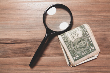 Wall Mural - agnifying glass and dollar banknotes with coins on wooden background, top view, money