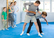 © JackF - Concentrated man with trainer in sport club during self-defense training, sparring and practicing technique of hand grab