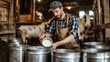 © NAIMAH - Farmer pouring milk into buckets in barn, cows in background, dairy farming