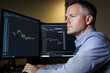 © Zape - A businessman sitting at a desk, analyzing stock data and making investment decisions on a computer screen.
