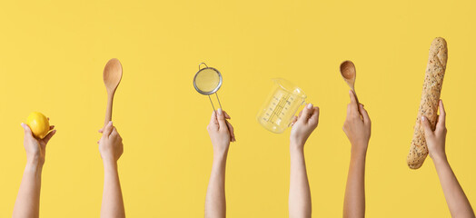 Wall Mural - Female hands with baking utensils and baguette on yellow background