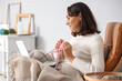 © Pixel-Shot - Young woman knitting with needles and laptop at home