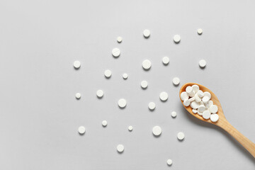 Wall Mural - Wooden spoon with pills on grey background