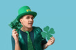 © Pixel-Shot - Young man in green clothes, with gift and shamrock on blue background. St. Patrick's Day