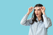 © Pixel-Shot - Surprised young woman putting off eyeglasses on blue background
