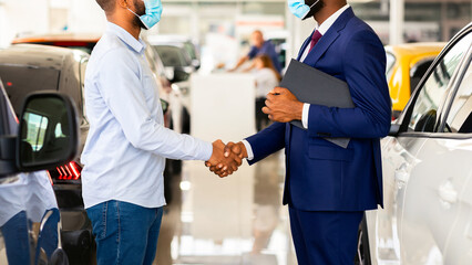 Wall Mural - Car Dealership. Black Salesperson In Medical Mask Car Sales. Shaking Hands With Male Customer In Modern Showroom, Happy African American Man Buying New Automobile During Coronavirus Pandemic