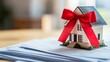 © Copyspace - House is sitting on top of a stack of papers with a red ribbon tied around it